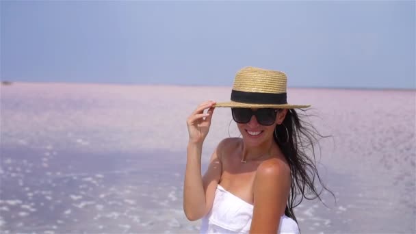 Donna in cappello cammina su un lago salato rosa in una giornata estiva soleggiata. — Video Stock