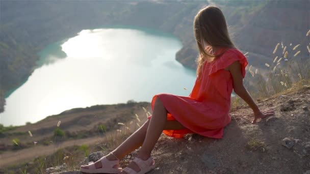 Little girl near the lake at the day time with amazing nature on background — Stock Video