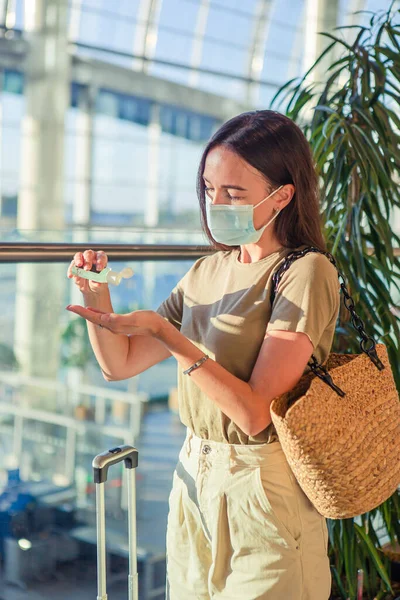 Młoda turystka w masce medycznej z bagażem na lotnisku międzynarodowym — Zdjęcie stockowe