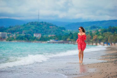 Plajda beyazlar içindeki genç kadın.