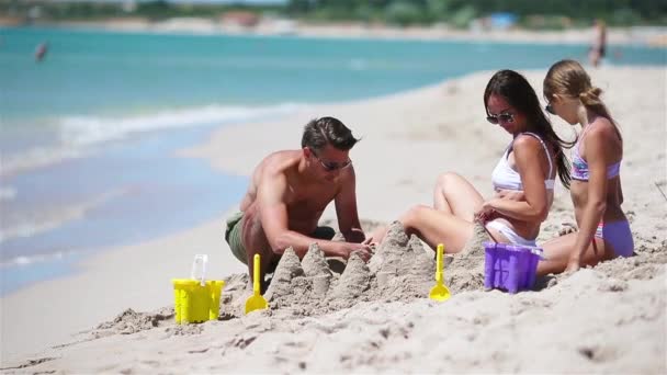 Otec a děti staví hrad z písku na tropické pláži. Rodinné hraní s hračkami na pláži — Stock video
