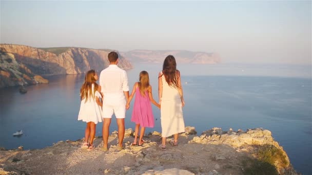 Família feliz de quatro caminhando nas montanhas ao pôr do sol — Vídeo de Stock