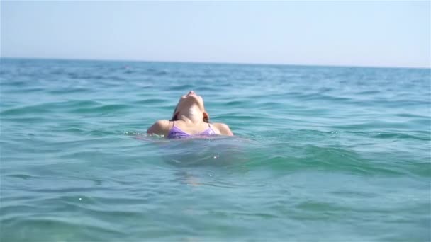 여름휴가 때 행복 한 어린이가 열대 해변에서 파도를 타고 노는 모습. 바다에서 노는 소녀. — 비디오