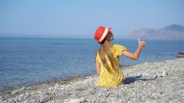 Schattig klein meisje aan het strand tijdens de zomervakantie — Stockvideo