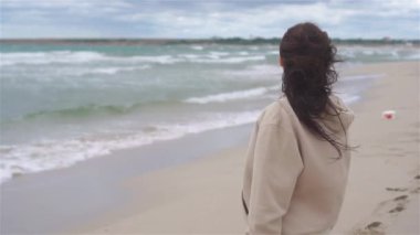 Plajda beyazlar içindeki genç kadın.