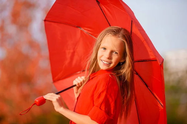 Ragazza felice bambino ride sotto ombrello rosso — Foto Stock