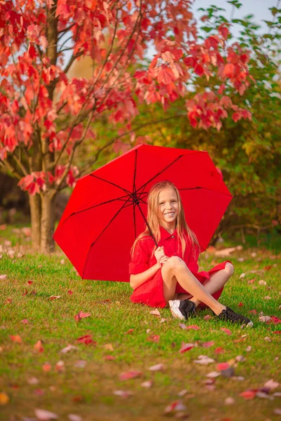 Happy child girl laughs under red umbrella — Stock Photo, Image