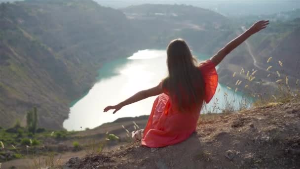 Μικρό κορίτσι κοντά στη λίμνη κατά τη διάρκεια της ημέρας με καταπληκτική φύση στο παρασκήνιο — Αρχείο Βίντεο