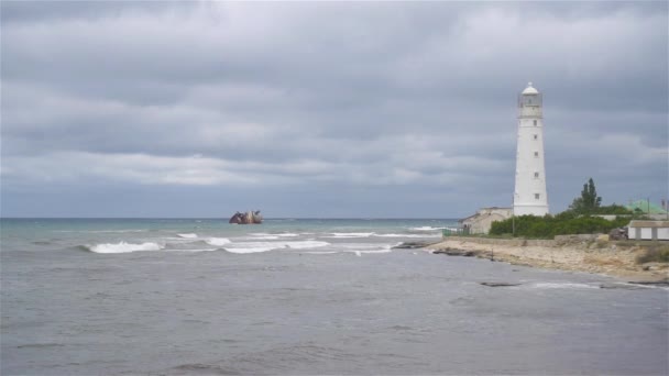 Sjølandskap med vakkert hvitt fyrtårn mot stormfullt sk og hav – stockvideo