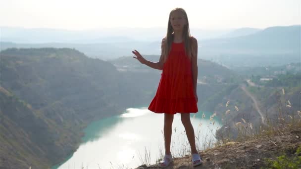 Niña cerca del lago durante el día con una naturaleza increíble en el fondo — Vídeos de Stock