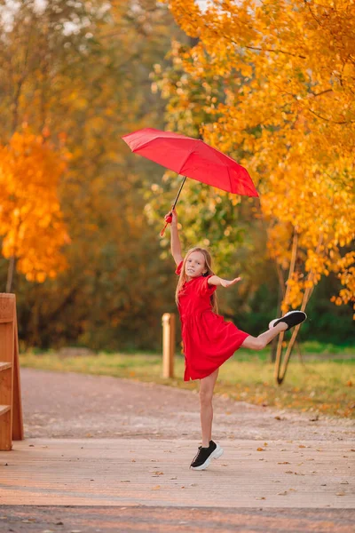 Lycklig barn flicka skrattar under rött paraply — Stockfoto