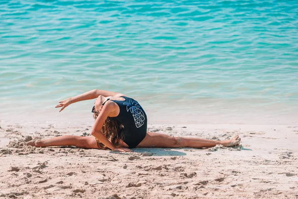 Активная девчонка на пляже, веселая. Милый ребенок делает спортивные упражнения на берегу моря — стоковое фото