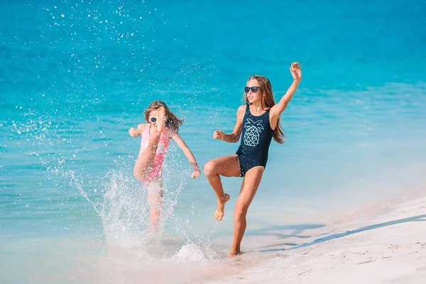 Pequeñas chicas divertidas felices tienen un montón de diversión en la playa tropical jugando juntos —  Fotos de Stock