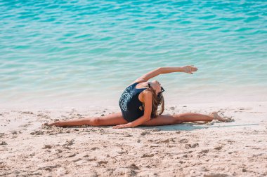 Sahilde hareketli küçük bir kız çok eğleniyor. Deniz kıyısında spor egzersizleri yapan tatlı çocuk.
