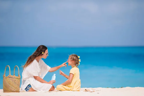 Giovane madre che applica la crema solare al naso figlia sulla spiaggia. Protezione solare — Foto Stock