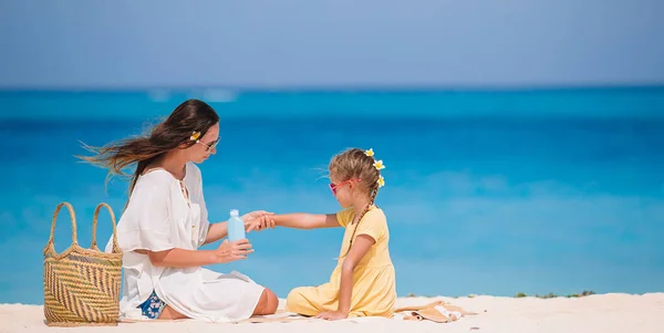 Young mother applying sun cream to daughter nose on the beach. Sun protection — Stock Photo, Image