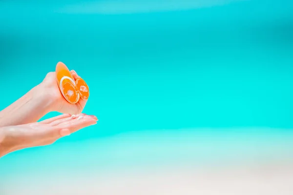 Hermosa joven sosteniendo una crema solar acostada en la playa tropical — Foto de Stock