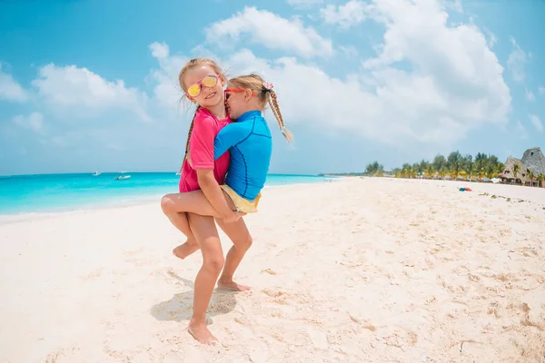 Twee kleine gelukkige meisjes hebben veel plezier op tropische strand spelen samen — Stockfoto