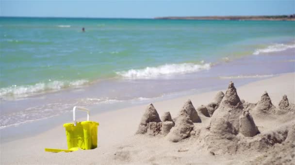 Zandkasteel op wit tropisch strand met plastic kinderspeelgoed — Stockvideo