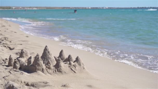 Песчаный замок на белом тропическом пляже с пластиковыми игрушками для детей — стоковое видео