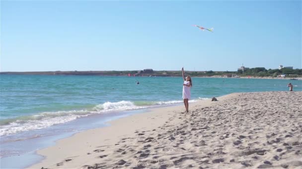 Liten flicka flyger en drake på stranden vid solnedgången — Stockvideo