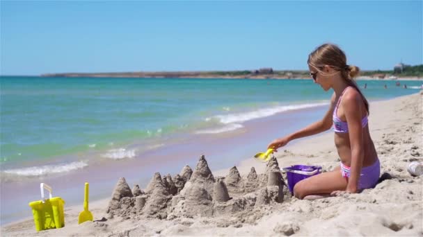 Tropik beyaz sahildeki küçük kız kumdan kale yapıyor. — Stok video