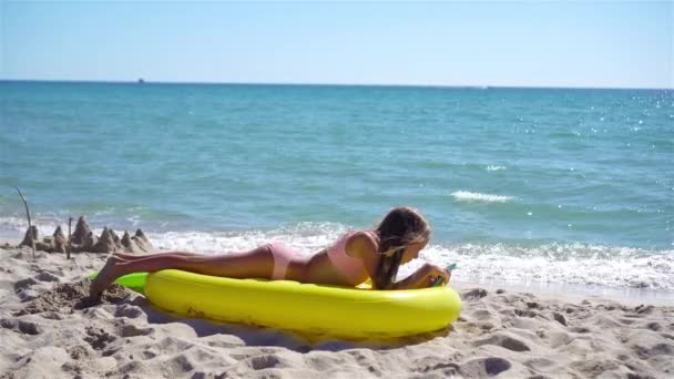 해변에 있는 푹신 푹신 한 공기 매트리스에 앉아 있는 사랑 스러운 소녀 — 비디오