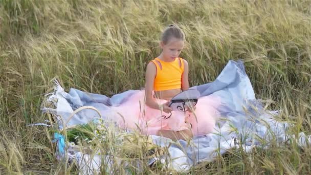 Чарівна дівчина дошкільнята, що щасливо ходить у пшеничному полі в теплий і сонячний літній день — стокове відео