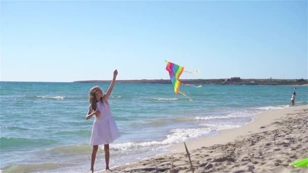 Little girl flying a kite on beach at sunset — Stock Video