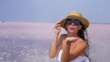 Güneşli bir yaz gününde pembe tuz gölünde yürüyen şapkalı bir kadın..