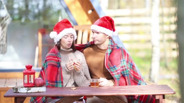 Young couple in red santa hat sitting on the wooden old table — Stock Video