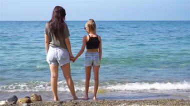 Güzel anne ve kız sahilde yaz tatilinin tadını çıkarıyorlar.