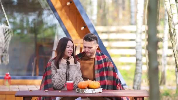 Молодая пара сидит на деревянном старом столе в осеннем лесу — стоковое видео