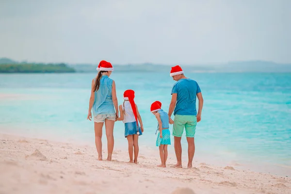 Szczęśliwa rodzina w czerwonych kapeluszach Santa na tropikalnej plaży z okazji świąt Bożego Narodzenia — Zdjęcie stockowe
