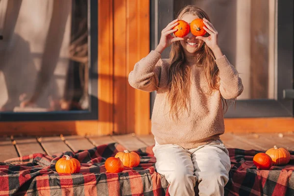 Hermosa chica cubrió sus ojos con calabazas en otoño día cálido — Foto de Stock