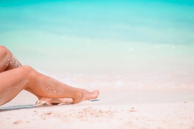 Kadınların ayakları sığ sularda beyaz kumsalda