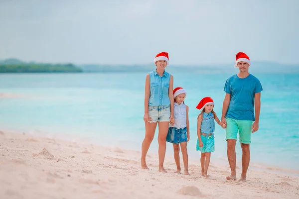Szczęśliwa rodzina w czerwonych kapeluszach Santa na tropikalnej plaży z okazji świąt Bożego Narodzenia — Zdjęcie stockowe