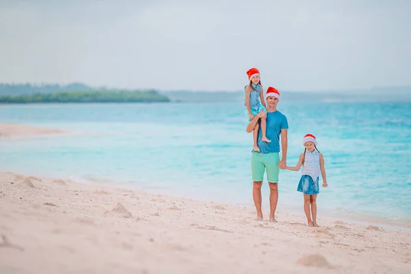 Glückliche Familie in roten Weihnachtsmützen an einem tropischen Strand feiert Weihnachtsurlaub — Stockfoto