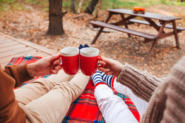 Hot cups of tea in hands in woollen sweater on background of cozy house — Stock Photo, Image