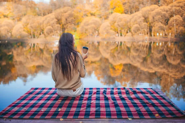 Осенняя концепция - красивая женщина пьет кофе в осеннем парке — стоковое фото
