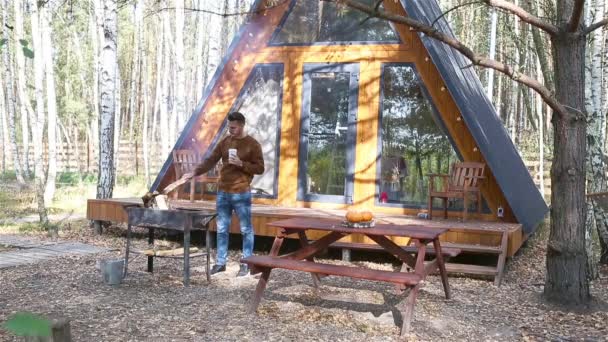 Молодий чоловік сидить на дерев'яному старому столі в осінньому лісі — стокове відео