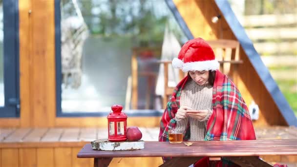 Junge Familie mit Weihnachtsmütze sitzt auf dem hölzernen alten Tischhintergrund ihres Hauses — Stockvideo