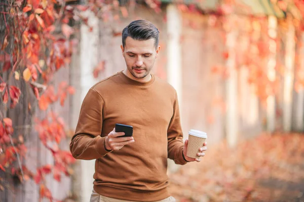 Jongeman die buiten koffie drinkt in het herfstpark — Stockfoto