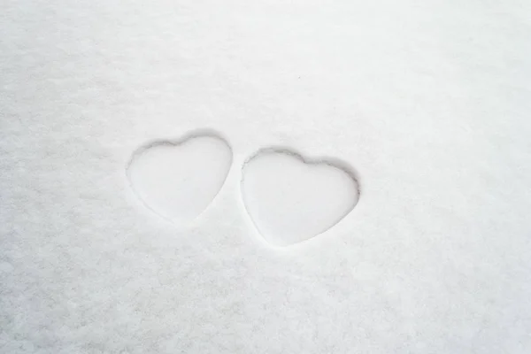 Two white hearts in snow. Minimalist Valentine\'s Day concept with outlines of two hearts in the snow. Mother\'s Day or Women\'s Day theme.