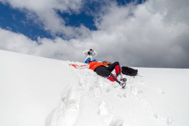İki diz derin karda bir kış yürüyüş tur sırasında (Karpat) Bucegi Dağları, Romanya, hemen altında bir sırt ile büyük, kabarık bulutlar üstlerindeki mola yorgun kadın yürüyüşçü ama mutlu.