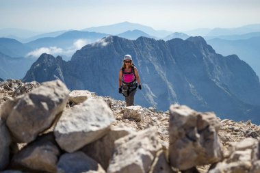 Kadın dağcı bitirme bir via ferrata rota üzerinde parlak, Slovenya ve İtalya arasındaki sınırda yer alan Triglav Ulusal Parkı, Julian Alps için Veliki Mangart (Mangrt) tepe üzerinde sıcak yaz günü.