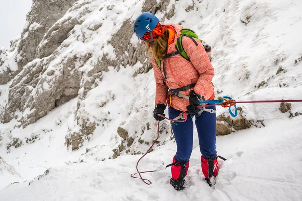 Genç kız abseiling bir tüp ipini tabak kullanarak taze karla, dar bir verdi içine dik kaya kaplı bir prusik sürtünme düğüm ile üzerinde Piatra Craiului dağlarında bir 7,8 mm ip Romanya yedeği