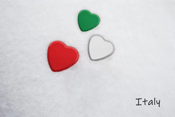Colores de la bandera italiana (español verde, blanco, Madder Lake / rojo) pintados en tres corazones. Fondo de nieve con el país, Italia, escrito en la parte inferior derecha. Concepto de cálida acogida en el turismo . — Foto de Stock