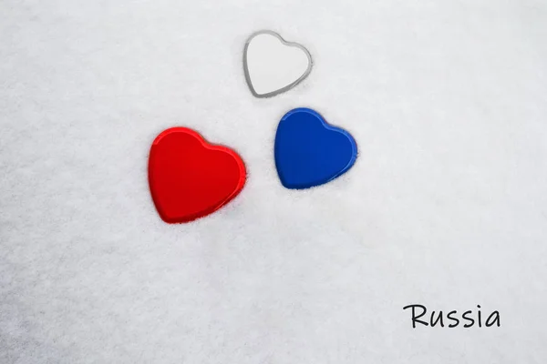Цвета российского флага (белый, филиппинский синий, максимальный красный) нарисованы на трех сердцах. Снежный фон со страной, Россией, написанный внизу справа. Концепция теплого приема в туризме . — стоковое фото