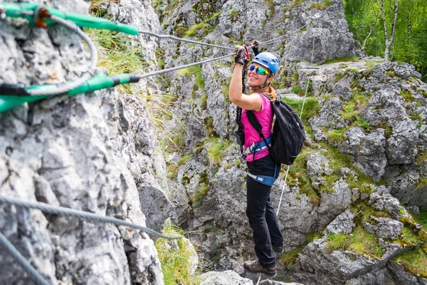 Šťastná dívka přejezd via ferrata visutý most v Baia de Fier, Rumunsko. Indiánský most na klettersteig s radostnou, dobrodružné ženy krokování přes něj. — Stock fotografie